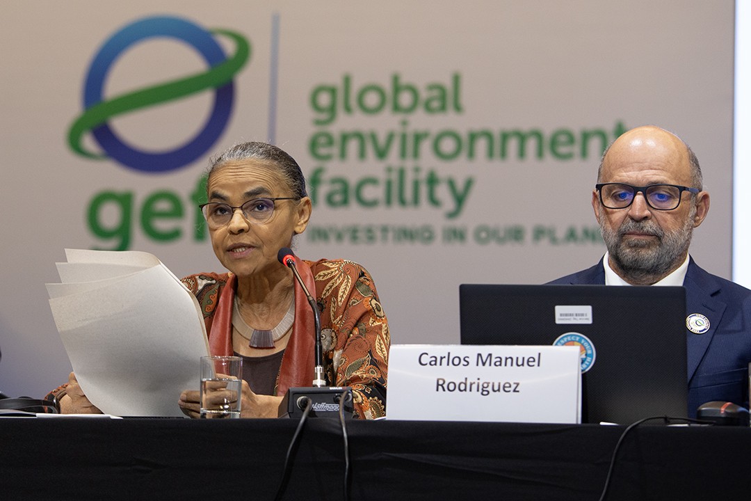 Carlos Manuel Rodríguez seated at the GEF Council table alongside Brazil's Environment Minister Marina Silva, with the Global Environment Facility logo visible behind them