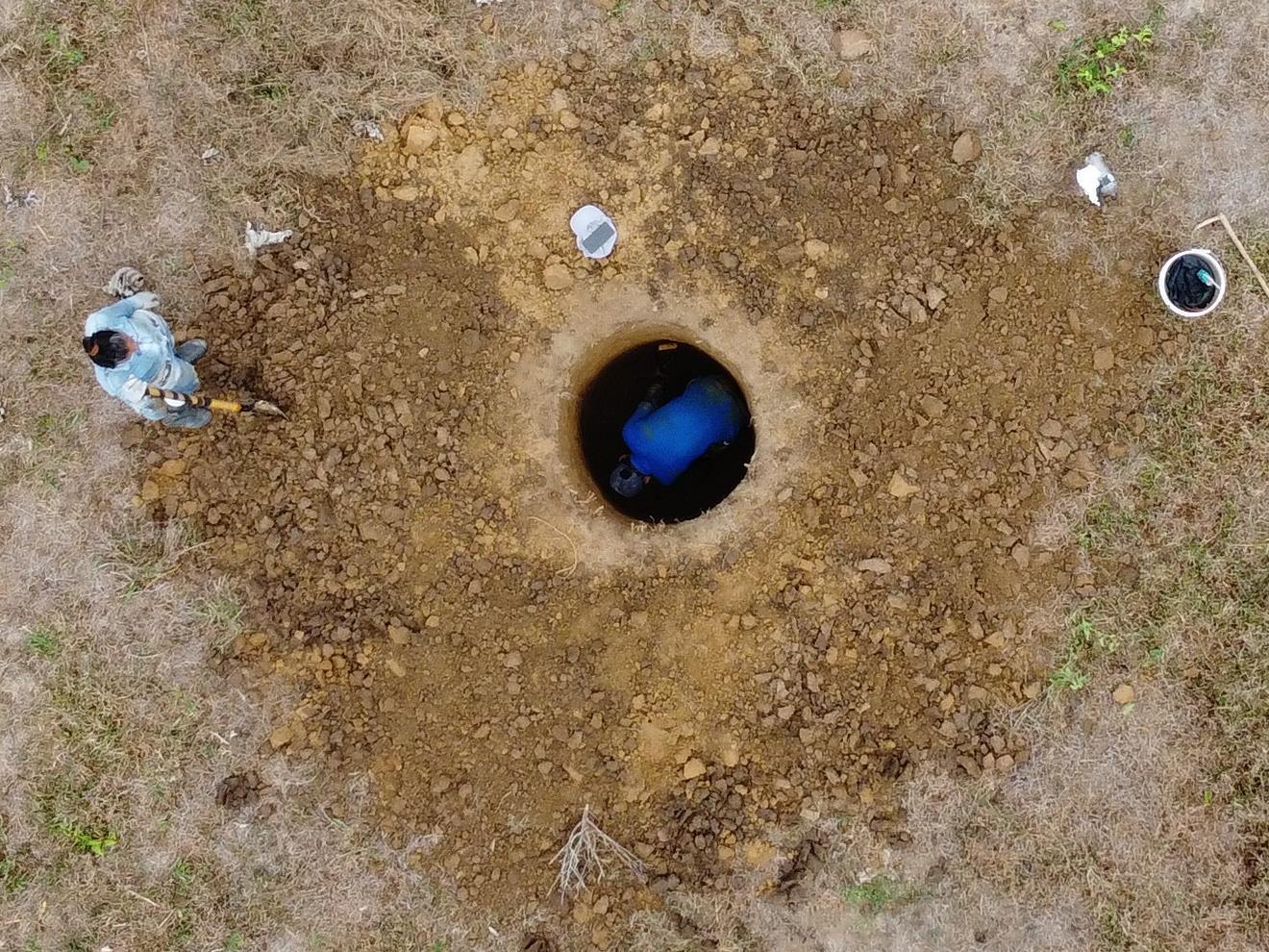 Aerial drone view of archaeologists excavating multiple circular test pits