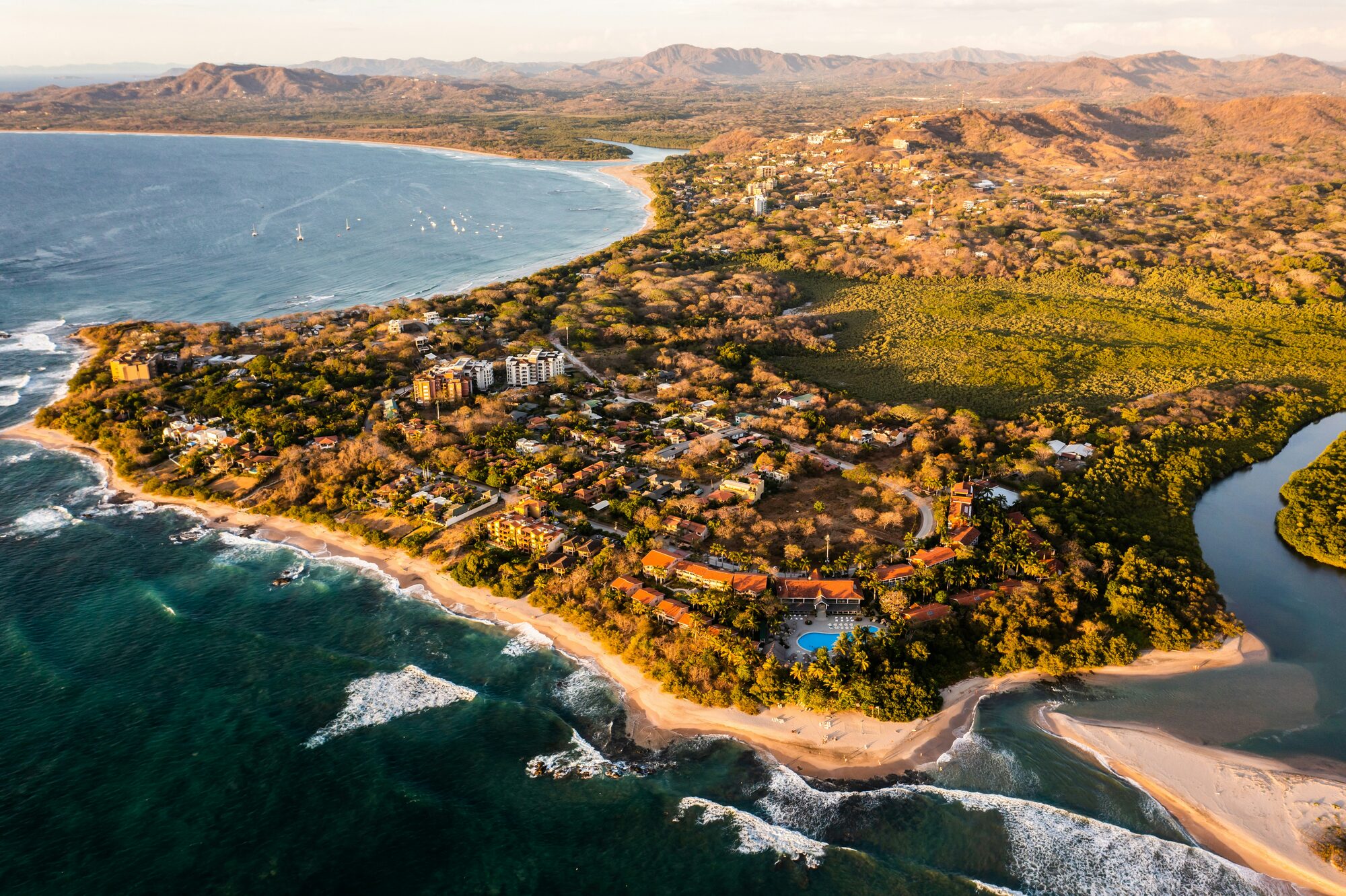 Aerial view of Guanacaste coastline showing hotels, villas, and beach development at sunset