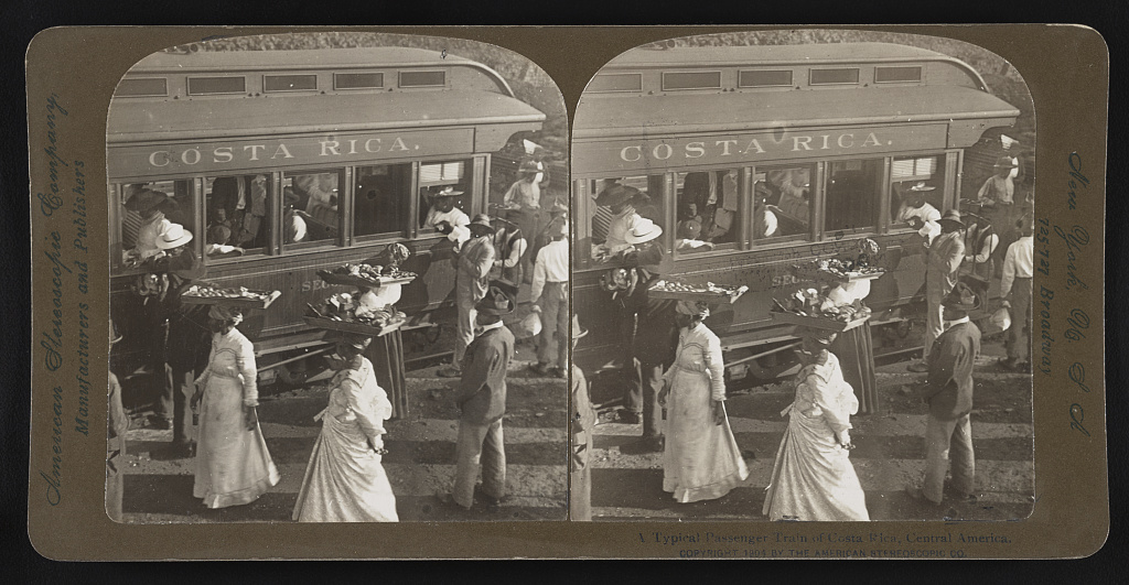Historical photograph of a Costa Rican passenger train from 1904 with vendors approaching