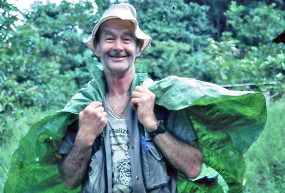 Wolf Guindon grinning under a giant leaf in the rain
